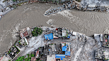 An aerial view shows A collapsed bridge and damaged settlements debris and mud covering an area following flash floods on August 28, 2026 in DeviGhat village, Nepal.