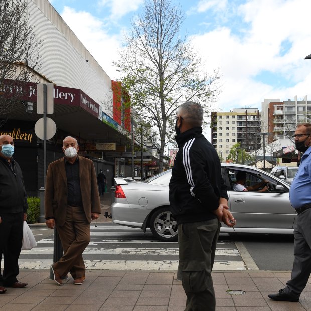 A group of elderly men greet each other from a distance at the Fairfield shopping strip.