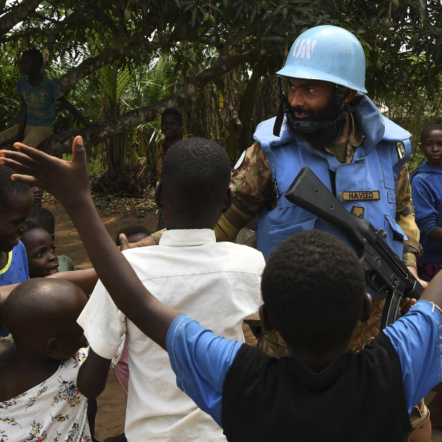 A United Nations peace keeper from Pakistan shakes hands with children while on patrol in a village near Kananga in Kasai Central. 