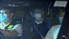 In this image made from video provided by TVB, Fung Wai-kong, centre, an editorial writer of the now-defunct Hong Kong pro-democracy newspaper Apple Daily sits in a police car after his arrest.