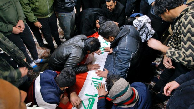 People mourn by the flag-draped coffin of a suicide bomb victim, Samer Hassan during his funeral procession at the Imam Ali shrine in Najaf, Iraq.