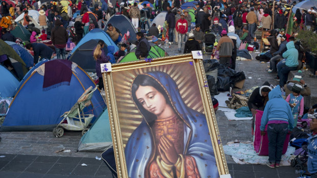 A pilgrim carries on his back a framed image of the Virgin of Guadalupe at the Basilica of Guadalupe in Mexico City.
