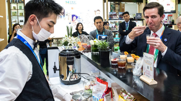 Trade Minister Simon Birmingham trying vitamin drinks at the Swisse stand on day one of the China International Import Expo in Shanghai this week.