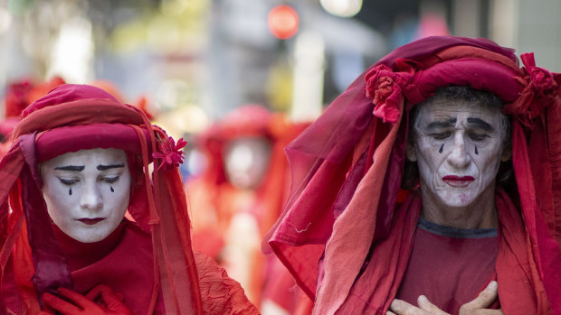 The Red Rebels, a sub-group of Extinction Rebellion, performs in the Brisbane CBD on Tuesday.
