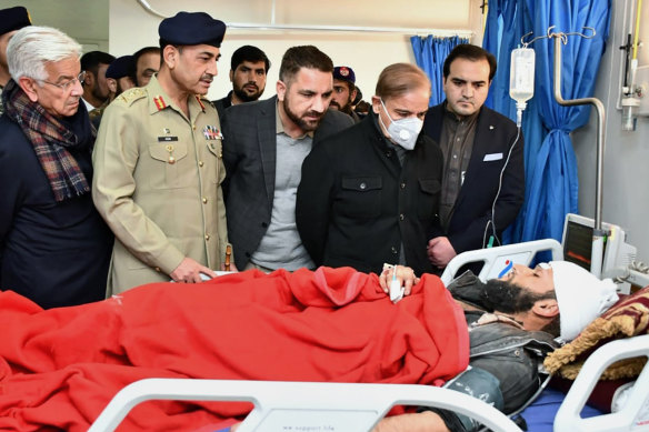 Pakistan’s Prime Minister Shehbaz Sharif (second from right) and Army Chief General Asim Munir (second from left) talk with an injured victim.