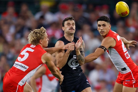 Zac Williams handballs between two Swans. 