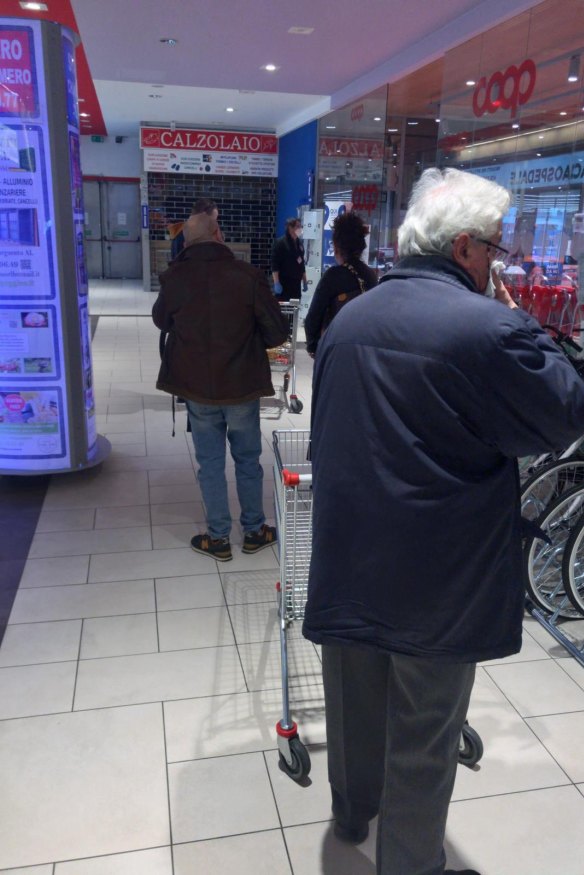 People in line for a supermarket in Alessandria. Only 10 people are allowed in at a time and must stand 1.5 metres apart while waiting in line. 