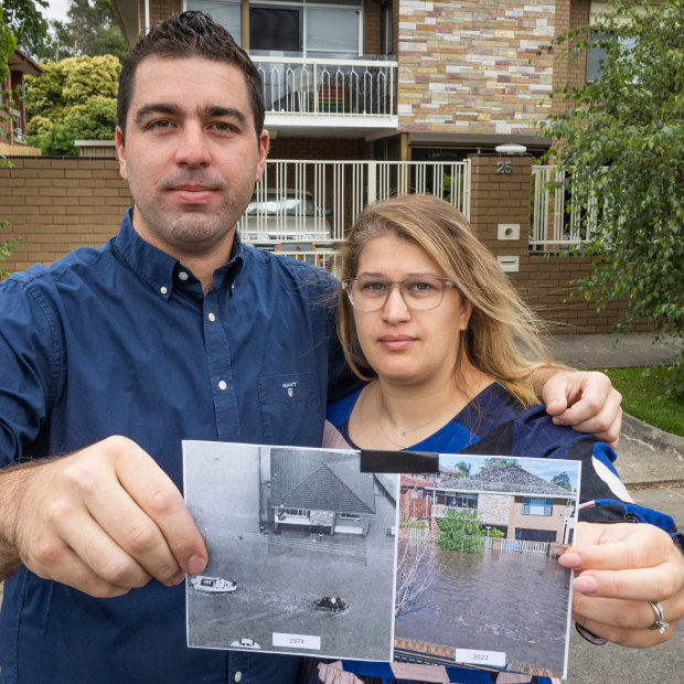 Lee and Selin Lanzafame holding up two images of their flooded home, taken 48 years apart.