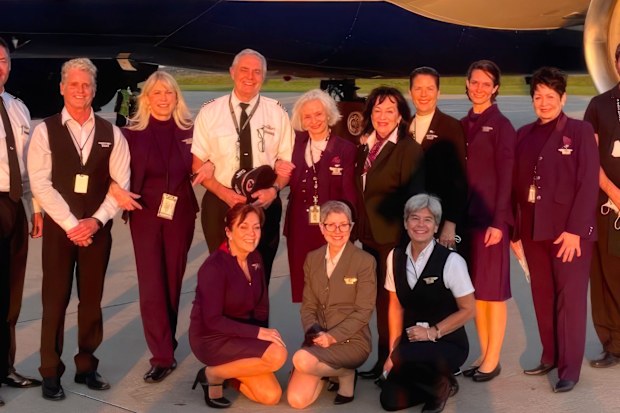 A group of flight attendants in uniform standing on the tarmac
