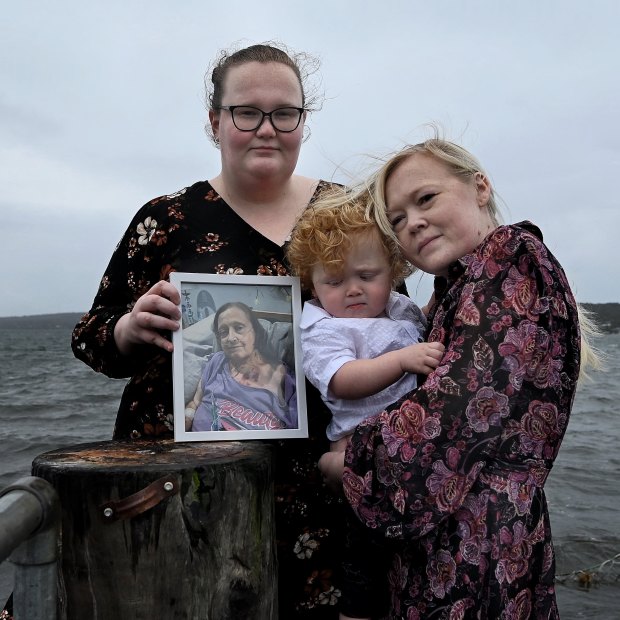 Sisters Temperance Gollan and Morgan Scivyer (holding her two-year-old son Zale Scivyer) with a photo of their mother Kim Gollan.