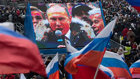 Attendees wave Russian flags in support of President Vladimir Putin as he speaks on screen during a pre-election rally at Luzhniki stadium in Moscow in March. 