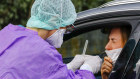A doctor takes a nasal swab from a patient at a drive-in coronavirus testing clinic in Germany.