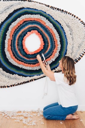 Textile artist Tammy Kanat with one of her woven abstract wall-hangings.