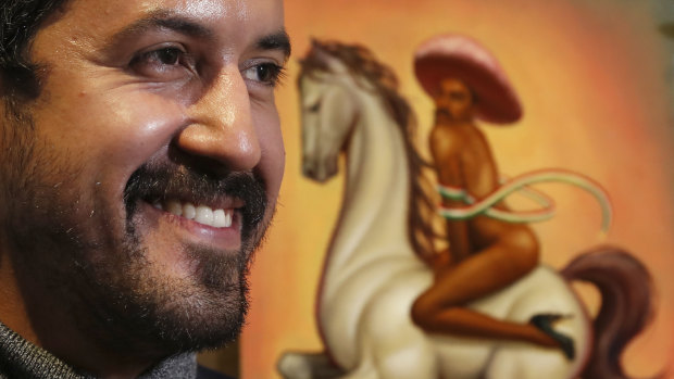 Mexican artist Fabian Chairez stands next to his painting of Mexican Revolution hero Emiliano Zapata straddling on a horse nude, wearing high heels and a pink, broad-brimmed hat. 