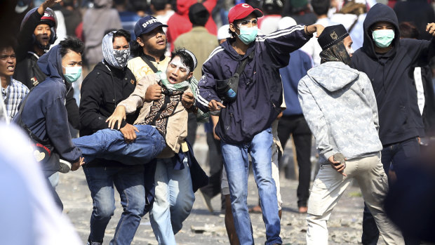 Supporters of Indonesian presidential candidate Prabowo Subianto carry an injured man during a clash with Indonesian police in Jakarta.