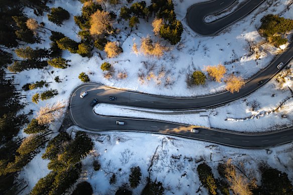 A bird’s-eye view of vehicles negotiating the curving Maloja Pass in a wintry Swiss Alps.