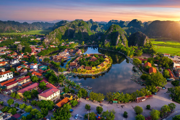 Discover a tapestry of jade-green rice paddies and muddy villages against a backdrop of blue hills. (Pictured: Tam Coc, just outside of Hanoi)