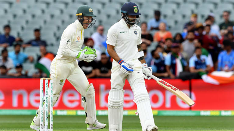 Australian captain Tim Paine celebrates as Indian captain Virat Kohli leaves the field after being dismissed by Australian bowler Nathan Lyon for 34 runs.