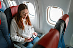 Female traveler sitting by the window in aircraft and fastening safety belt