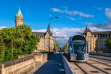 Luxembourg city - a street with the Clock tower and Adolphe bridge and a tram