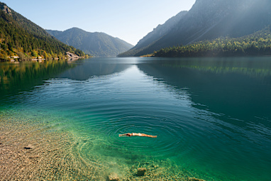 Carefree woman swimming in Alpine mountain lake in summer