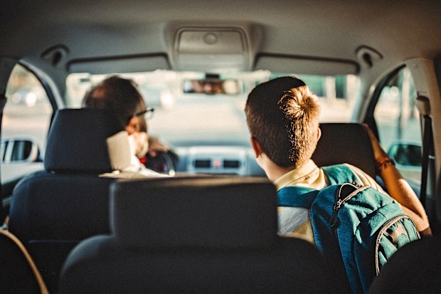 Teen boy in car being driven to school by dad.