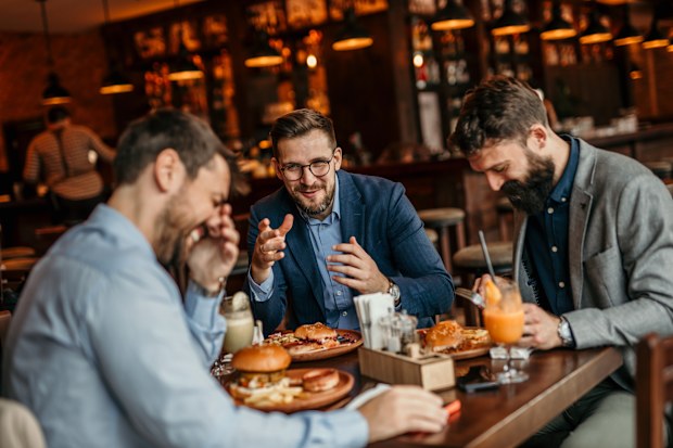 Group of businessmen enjoying a burger lunch while discussing work matters