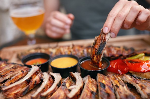 Stock image of someone eating ribs in a restaurant