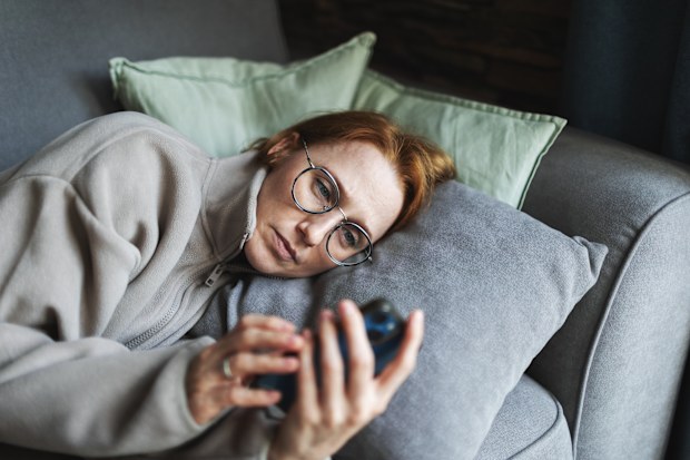 Mia adult woman lying in bed with mobile, sad and depressed, bad news