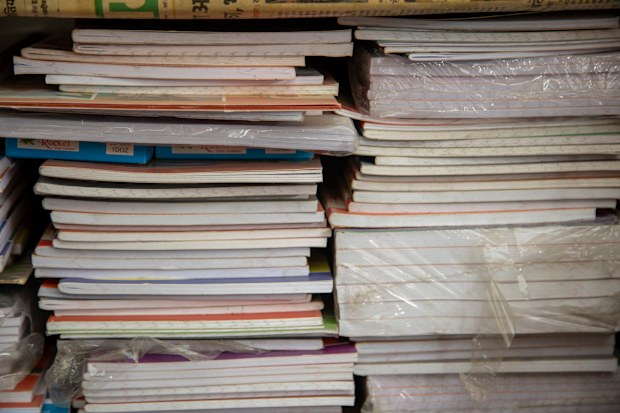 Organized notebooks and papers neatly stacked on shelves, displaying varying colors and textures, useful for education, office, or creative purposes.