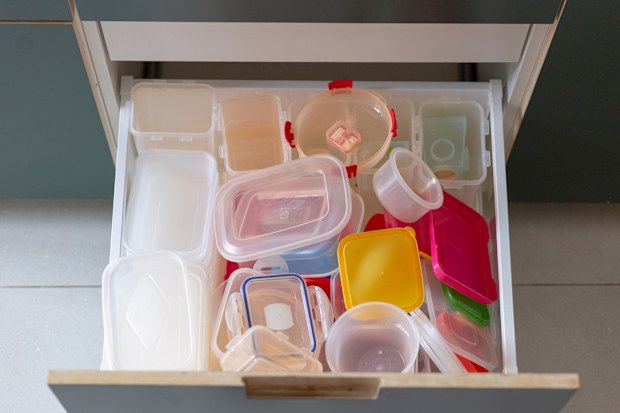 A kitchen drawer full of a large amount of plastic Tupperware containers.
