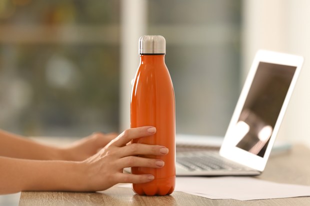 Woman with orange thermos bottle at workplace