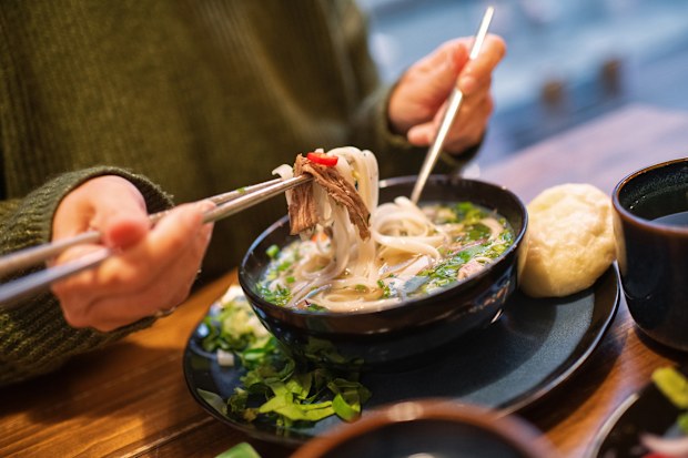 Close-up of a woman eating Vietnamese dish Pho Bo soup in a cafe