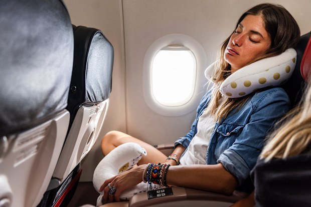 A young woman is peacefully napping on the airplane seat
