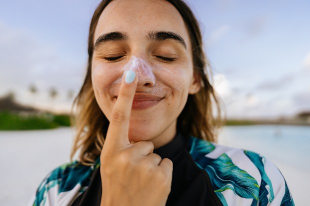 Stock image of a young woman applying sunscreen
