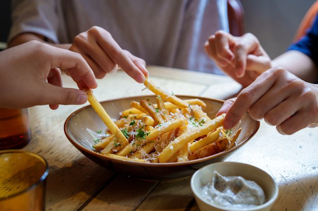 Stock photo of friends sharing a bowl of hot chips