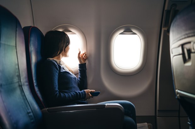 Young woman sitting in an airplane, waiting for a flight to start, looking through airplane window,