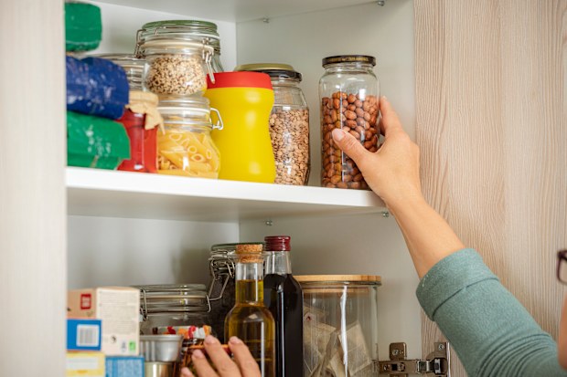 Female hand picking ingredient for cooking from kitchen cabinet