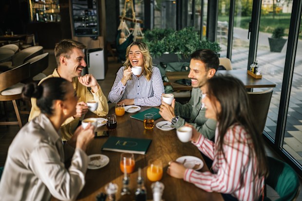 Happy friends drinking coffee and juices in a restaurant. Hanging out and having fun together.