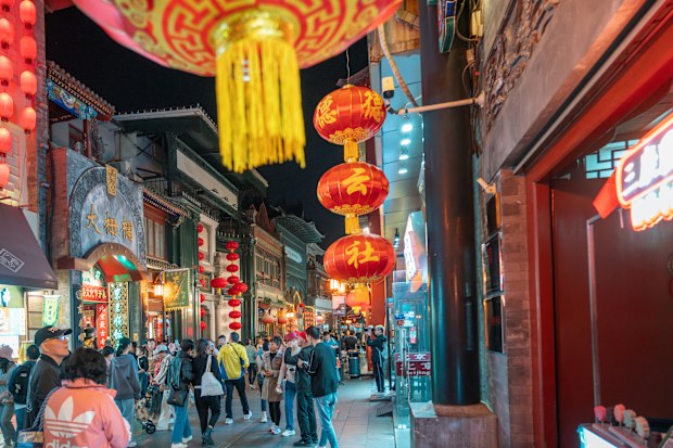 A bustling Beijing night market scene filled with red lanterns, colorful shops, and crowds. Neon signs and festive decor illuminate narrow streets, capturing lively urban culture and traditional charm.