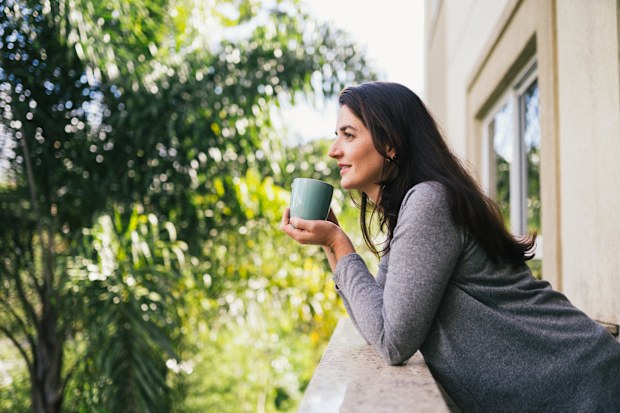 woman quietly drinking coffe on a break on her balcony