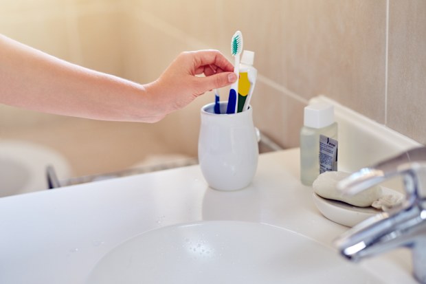 Woman using a toothbrush in a holder in a bathroom at home