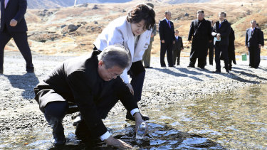 South Korean President Moon Jae-in puts water from the crater lake into a bottle as his wife Kim Jung-sook watches.
