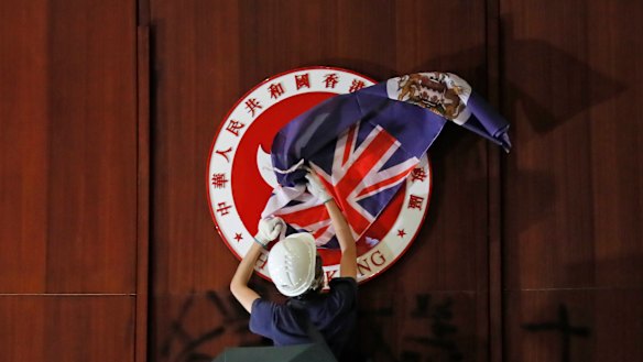 A protester covers the Hong Kong emblem with the Hong Kong colonial flag in the Legislative Council chambers during protests on Monday.