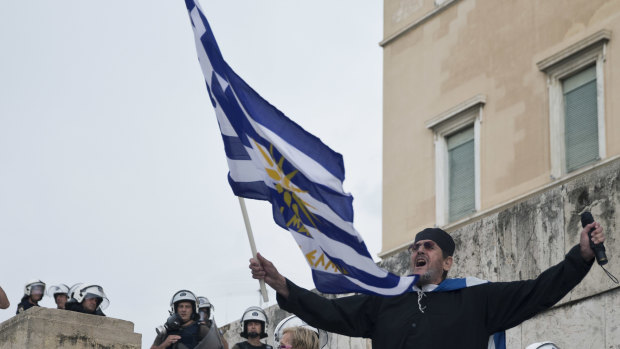 A Greek Orthodox monk waves a Greek flag during a protest against the agreement between Greece and Macedonia over dispute of the former Yugoslav's republic name, outside the Greek Parliament, in Athens, Saturday.