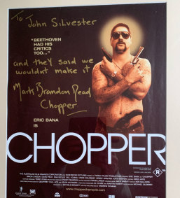 Life imitating art. Chopper Read signs a poster of Eric Bana playing Chopper Read.