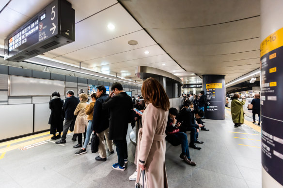 Train passengers queue at an underground station in Tokyo.