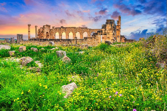 The sun sets overr outer wall of the ancient Roman  basilica, with its  Corinthian columns, at Volubilis, Morocco.