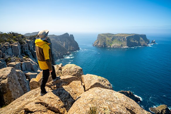 A Three Capes Track walker in Tasmania beholds the rugged coastline  bordering the Tasman National Park.
