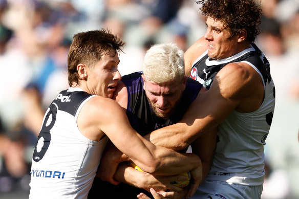 Luke Ryan of the Dockers is tackled by Lachie Fogarty (left) and Charlie Curnow of the Blues.